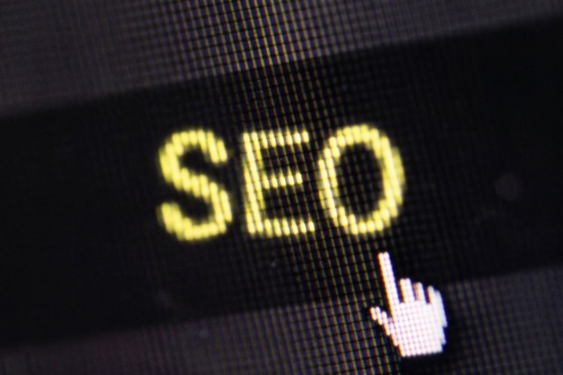 Gros plan sur le mot SEO affiché en jaune sur un écran, survolé par un curseur